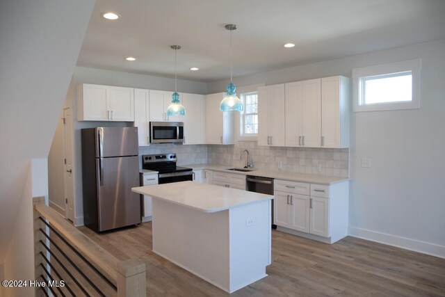 kitchen with sink, hanging light fixtures, stainless steel appliances, light hardwood / wood-style flooring, and white cabinets