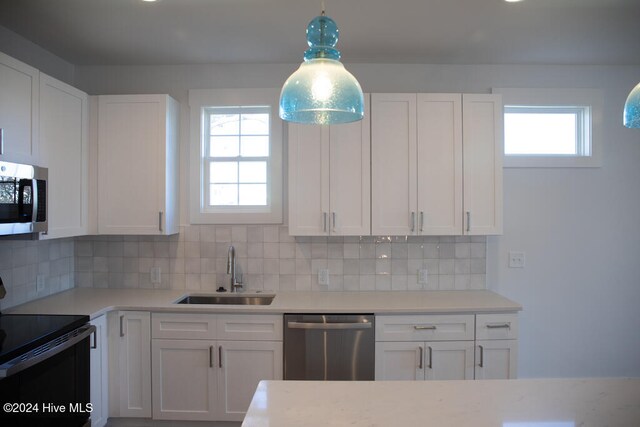 kitchen with appliances with stainless steel finishes, white cabinetry, plenty of natural light, and sink