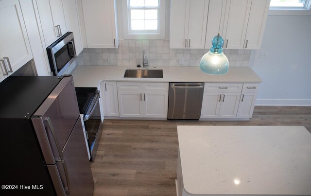 kitchen with backsplash, dark wood-type flooring, sink, appliances with stainless steel finishes, and white cabinetry