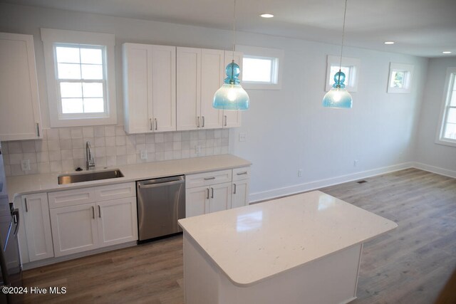 kitchen with sink, hanging light fixtures, stainless steel dishwasher, wood-type flooring, and white cabinets