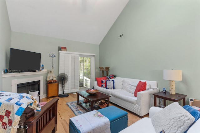 living room featuring high vaulted ceiling and light hardwood / wood-style flooring