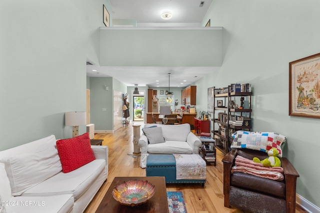 living room with a towering ceiling and light hardwood / wood-style flooring