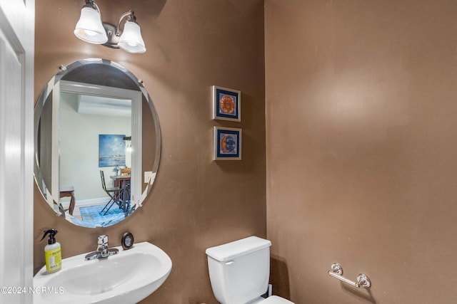 bathroom featuring an inviting chandelier, toilet, and sink