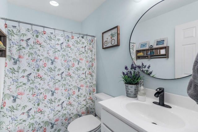 bathroom with curtained shower, vanity, and toilet