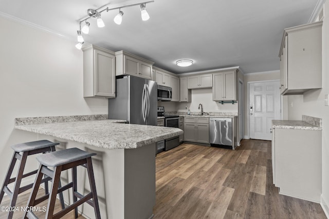 kitchen featuring gray cabinetry, a kitchen bar, kitchen peninsula, and appliances with stainless steel finishes