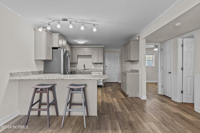 kitchen with kitchen peninsula, a kitchen bar, gray cabinetry, appliances with stainless steel finishes, and dark hardwood / wood-style flooring