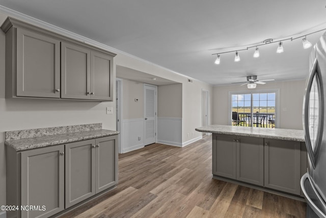 kitchen with gray cabinets, wood-type flooring, ceiling fan, and stainless steel refrigerator