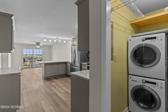 clothes washing area with ceiling fan, light wood-type flooring, and stacked washer / dryer