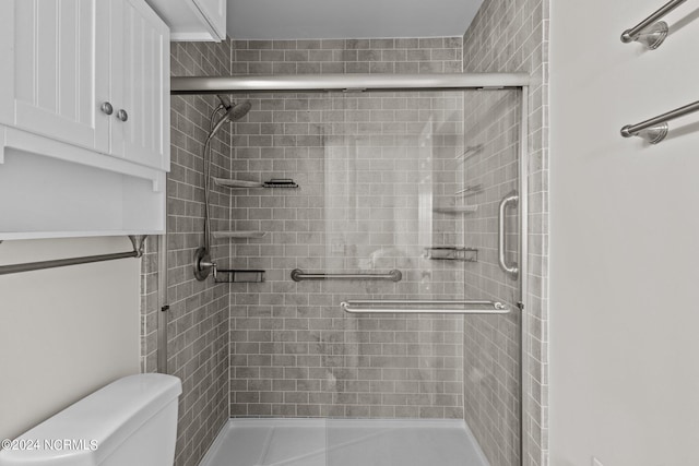 bathroom featuring toilet and a shower with shower door