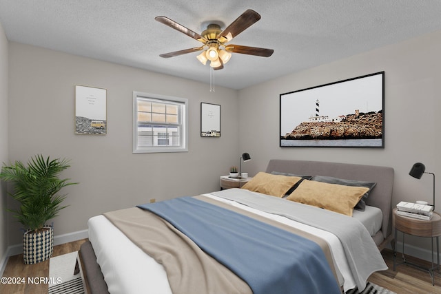 bedroom featuring wood-type flooring, ceiling fan, and a textured ceiling