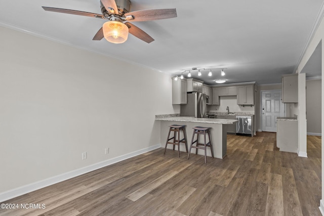 kitchen with dark wood-type flooring, kitchen peninsula, gray cabinetry, stainless steel appliances, and ornamental molding