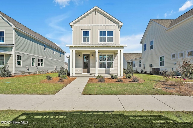 view of front of home featuring a porch, a front yard, and central AC