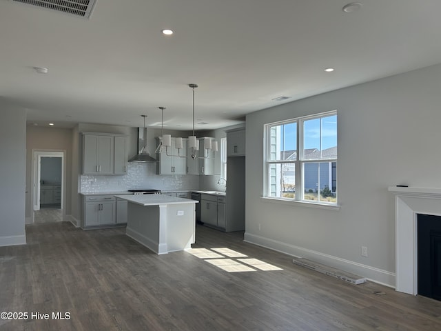 kitchen featuring tasteful backsplash, visible vents, a kitchen island, dark wood finished floors, and wall chimney exhaust hood