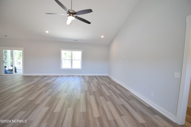 spare room featuring light hardwood / wood-style floors, vaulted ceiling, ceiling fan, and plenty of natural light