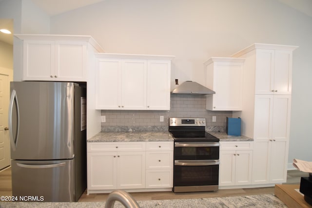 kitchen with appliances with stainless steel finishes, lofted ceiling, white cabinetry, and light stone counters