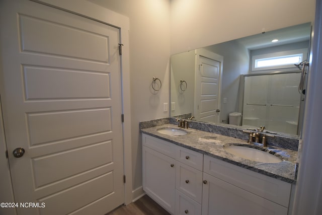 bathroom featuring hardwood / wood-style flooring, a shower with door, vanity, and toilet