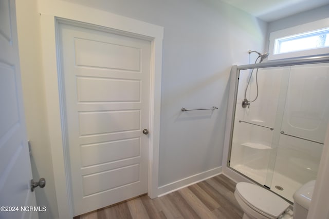 bathroom featuring walk in shower, hardwood / wood-style flooring, and toilet