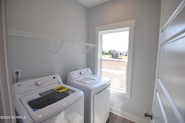 laundry area with a healthy amount of sunlight, washer and clothes dryer, and dark wood-type flooring