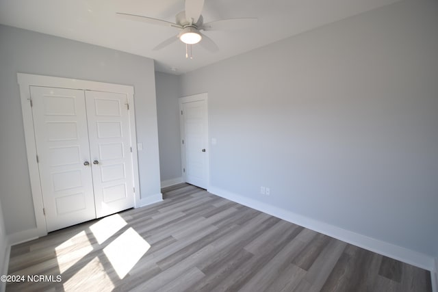 unfurnished bedroom with ceiling fan, light hardwood / wood-style flooring, and a closet