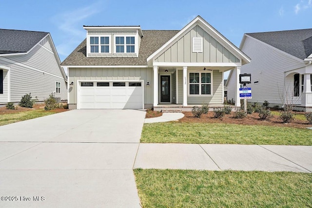 view of front of home featuring concrete driveway, covered porch, board and batten siding, and a front yard