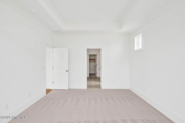 unfurnished room featuring crown molding, a raised ceiling, baseboards, and carpet floors