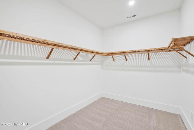 walk in closet with visible vents and light colored carpet