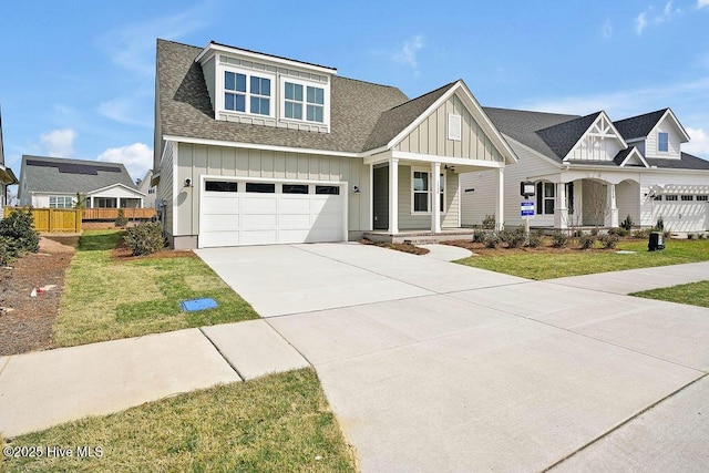 view of front of property featuring a front yard, a porch, concrete driveway, a garage, and board and batten siding