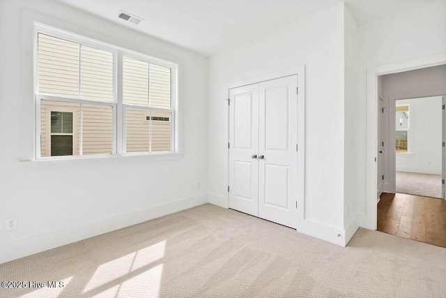 unfurnished bedroom featuring a closet, visible vents, carpet flooring, and baseboards