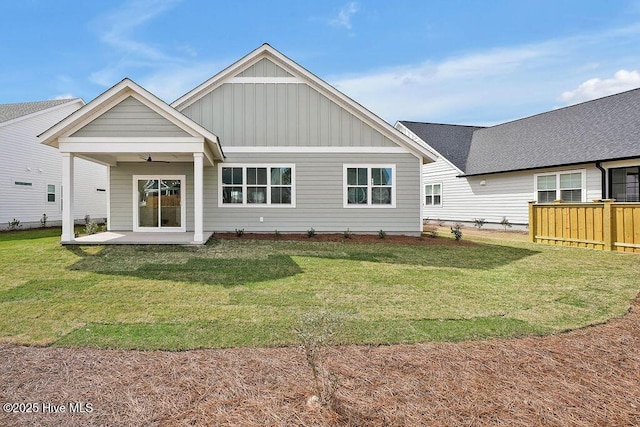 rear view of house with fence, a yard, ceiling fan, a patio area, and board and batten siding