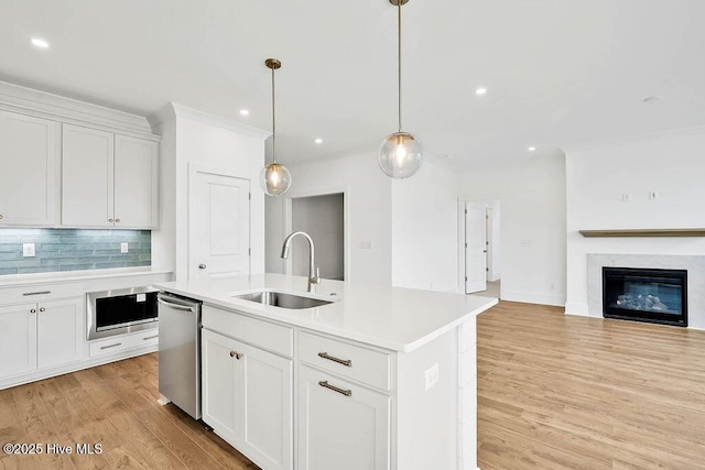 kitchen featuring light wood-style flooring, a sink, stainless steel dishwasher, light countertops, and decorative backsplash