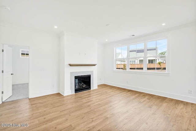 unfurnished living room featuring light wood-style flooring, baseboards, ornamental molding, and a fireplace