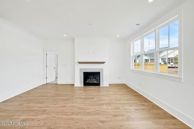 unfurnished living room featuring baseboards, ornamental molding, and light wood finished floors