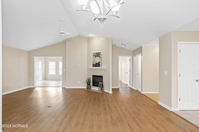 unfurnished living room with ceiling fan with notable chandelier, light wood-type flooring, and lofted ceiling