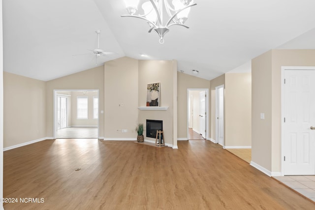 unfurnished living room with a glass covered fireplace, baseboards, light wood-type flooring, ceiling fan with notable chandelier, and vaulted ceiling