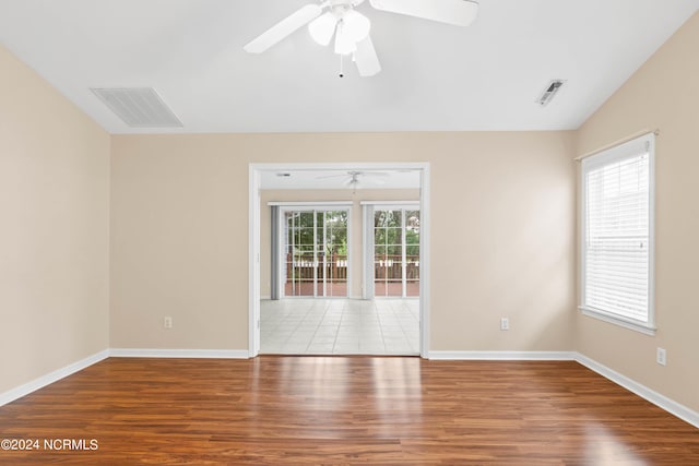 spare room with a ceiling fan, baseboards, visible vents, and wood finished floors