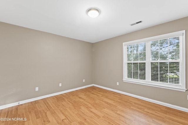 spare room with light wood-style floors, baseboards, and visible vents
