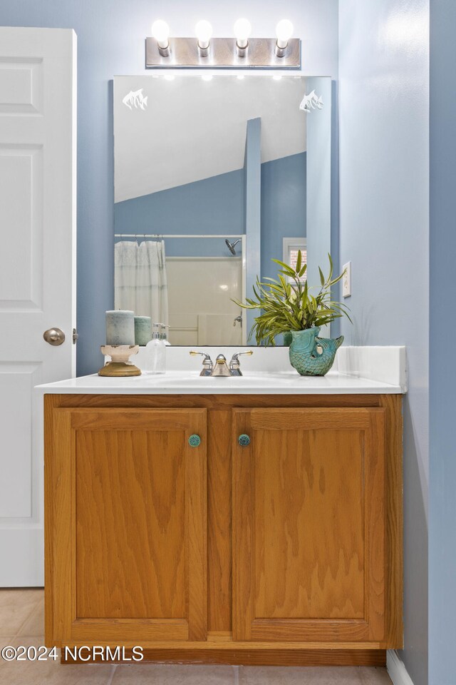 bathroom featuring a shower with shower curtain, vanity, vaulted ceiling, and tile patterned flooring