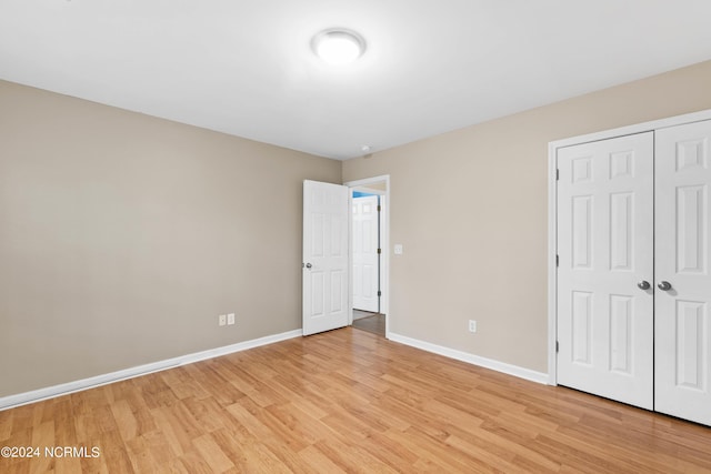 unfurnished bedroom with light wood-style floors, baseboards, and a closet