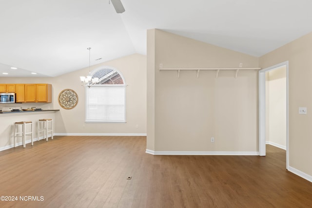 unfurnished living room featuring dark hardwood / wood-style flooring, an inviting chandelier, and lofted ceiling