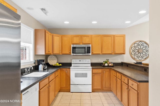 kitchen with light tile patterned floors, dark countertops, appliances with stainless steel finishes, and a sink