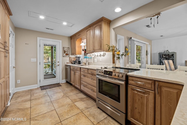 kitchen featuring light stone counters, sink, light tile patterned floors, and stainless steel appliances