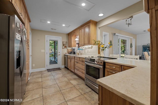 kitchen featuring kitchen peninsula, sink, light tile patterned flooring, and appliances with stainless steel finishes