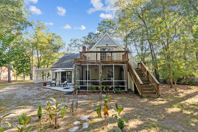 rear view of house featuring a wooden deck, a patio area, and a sunroom