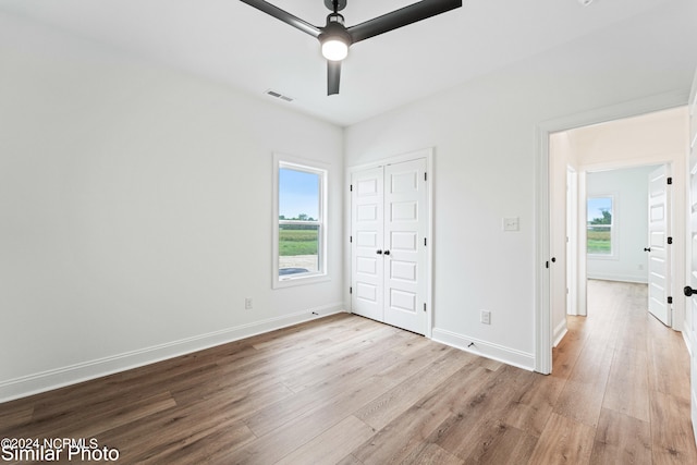 unfurnished bedroom featuring light hardwood / wood-style floors, multiple windows, and ceiling fan