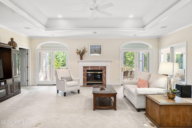 living room with light carpet, a raised ceiling, ceiling fan, and ornamental molding