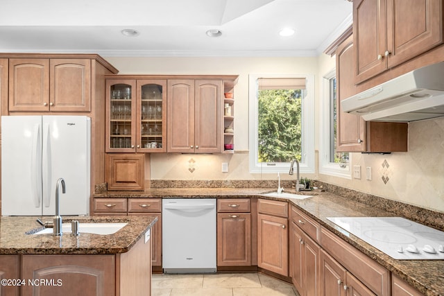 kitchen featuring light tile patterned flooring, white appliances, dark stone countertops, and sink