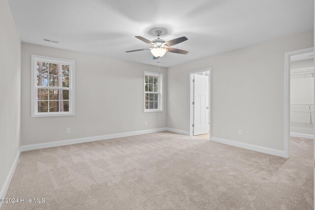 carpeted spare room with a wealth of natural light and ceiling fan