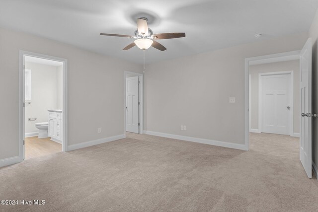 unfurnished bedroom with light carpet, connected bathroom, and ceiling fan