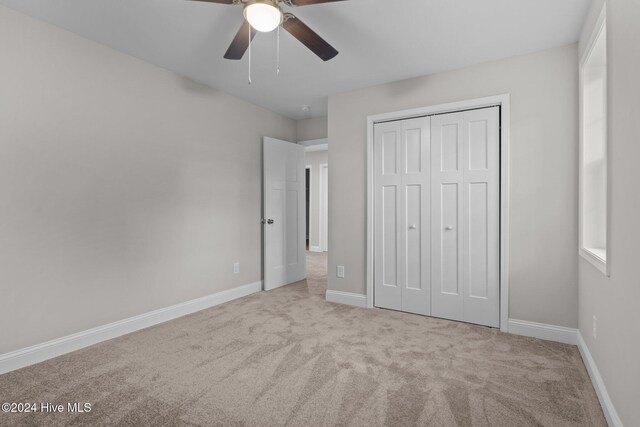 unfurnished bedroom featuring a closet, ceiling fan, and light colored carpet