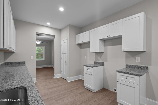 kitchen featuring dark stone counters, ceiling fan, white cabinets, and light hardwood / wood-style floors